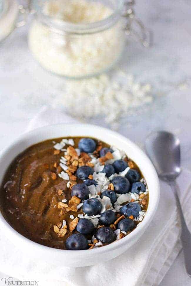 Chocolate Berry Smoothie Bowl  in a white bowl topped with granola, coconut and blueberries