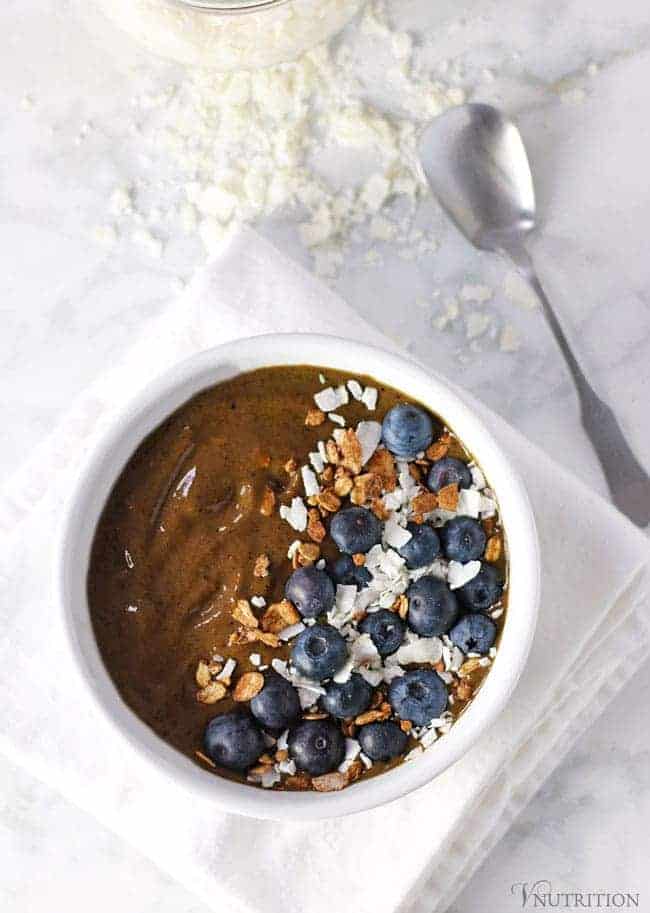 above shot of a Chocolate Protein Smoothie Bowl in a white bowl on a white napkin on a carrera marble table
