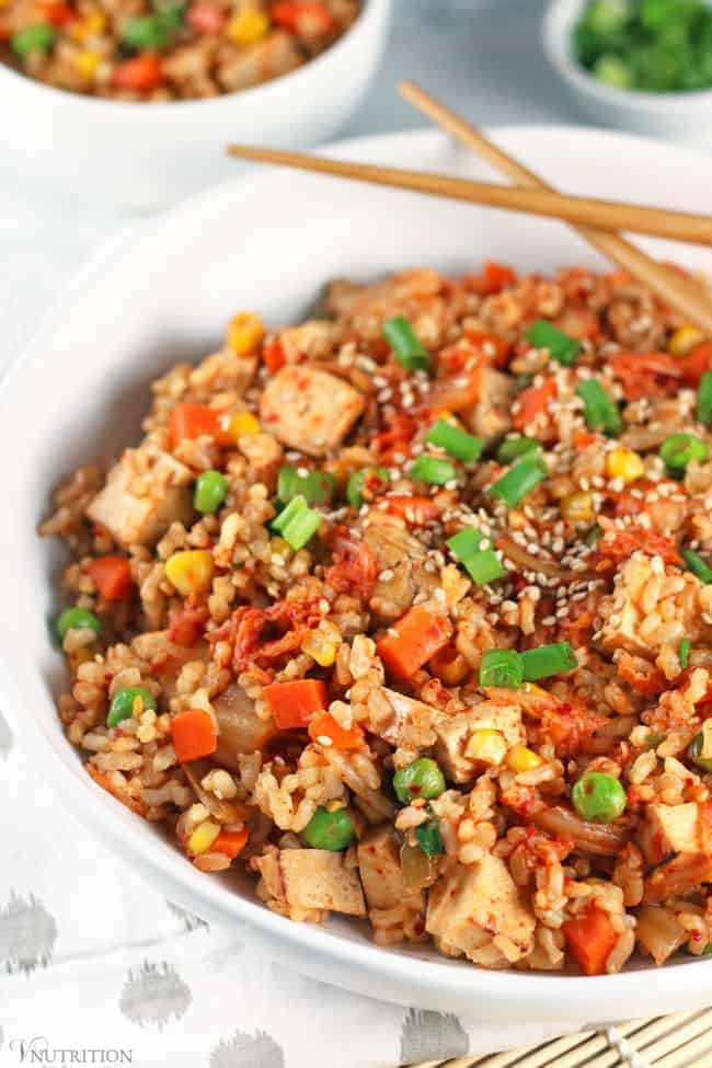 closeup of Kimchi Fried Rice in a white bowl with a pair of wooden chopsticks.