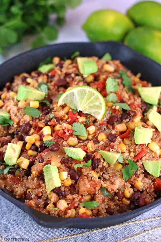 close up shot of Southwestern Quinoa skillet with fresh limes and cilantro bunch in the background