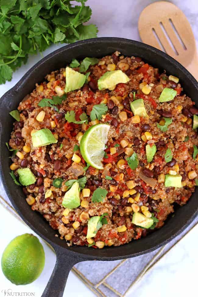overhead shot of Southwest Quinoa in a black cast iron skillet topped with avocado and fresh lime 