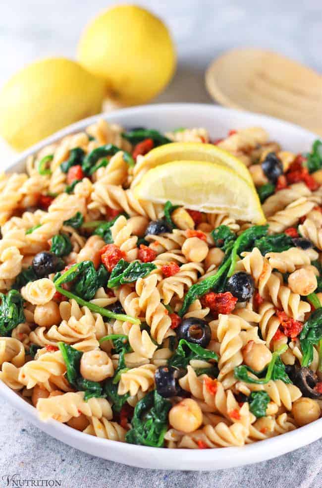 Vegan Pasta Salad with lemons and tongs in background.