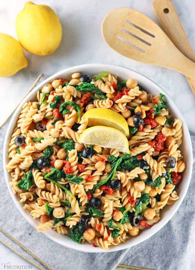 Easy Vegan Pasta Salad with lemons, tongs, and grey napkin.