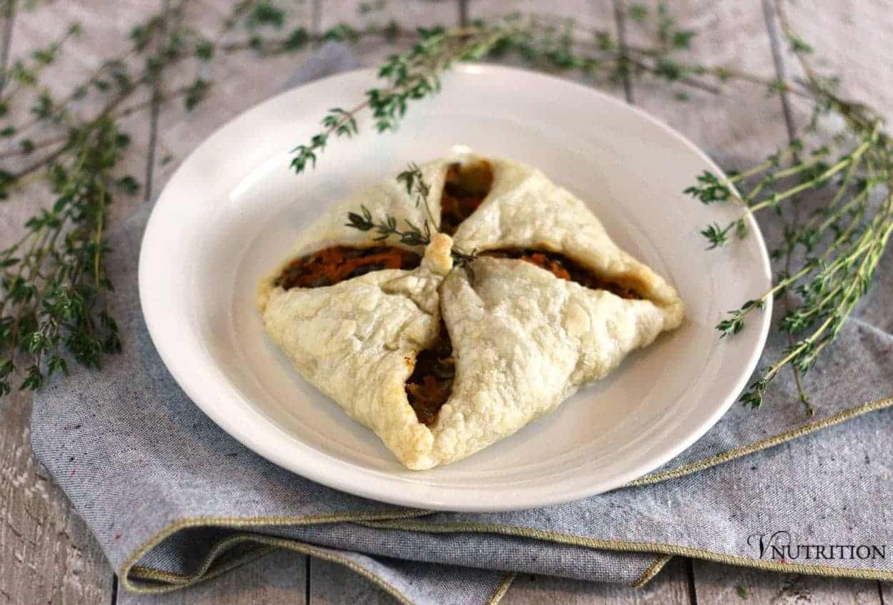 savory puff pastry recipe filled with lentil mixture on a white dinner plate with a grey napkin with gold edging. 