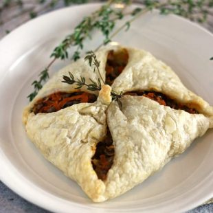 lentil puff pastry pocket on a white plate with fresh thyme garnish.