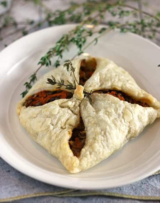 lentil puff pastry pocket on a white plate with fresh thyme garnish.