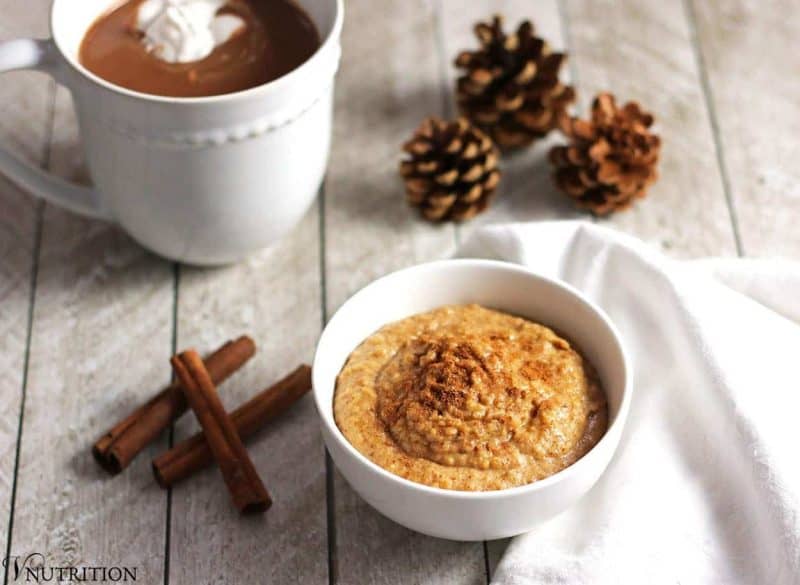 Snickerdoodle dessert hummus in a bowl with a white tea towel and cinnamon sticks.