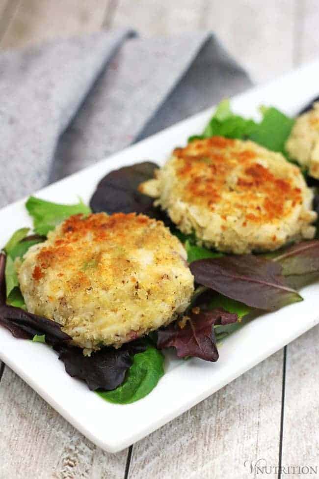 Vegan Crab Cakes on a bed of mixed greens on a rectangular white plate.