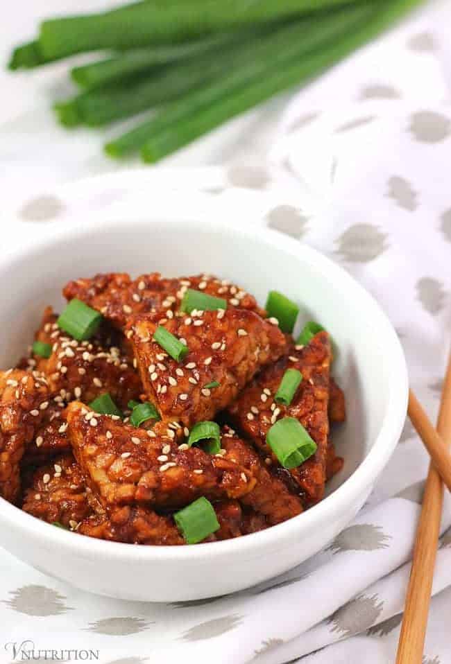 bowl of teriyaki tempeh with chopsticks and green onions in background