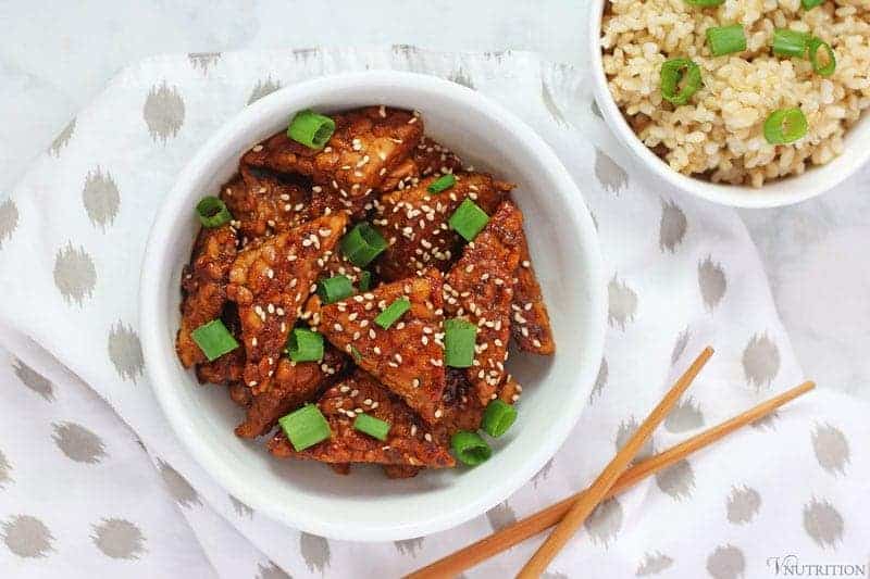 teriyaki tempeh in bowl with chopsticks and brown rice on napkin