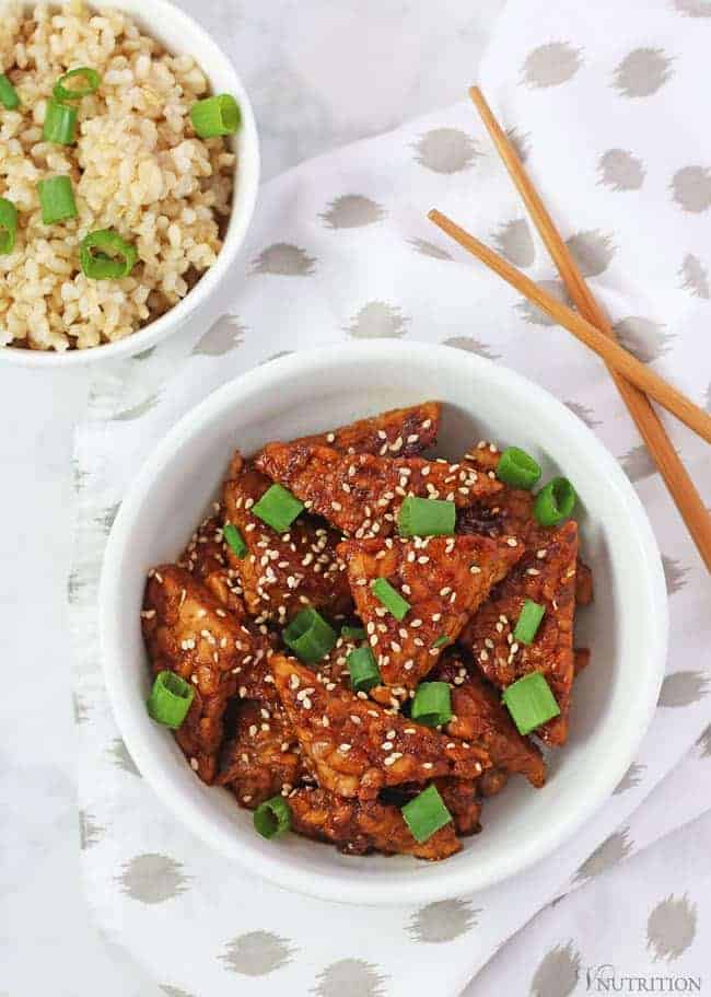 teriyaki tempeh with napkin, chopsticks and bowl of brown rice