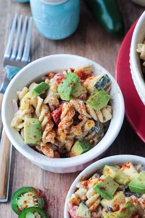 overhead closeup of southwest pasta salad with utensils, jalapeno peppers and salt for vegan sides for grilling