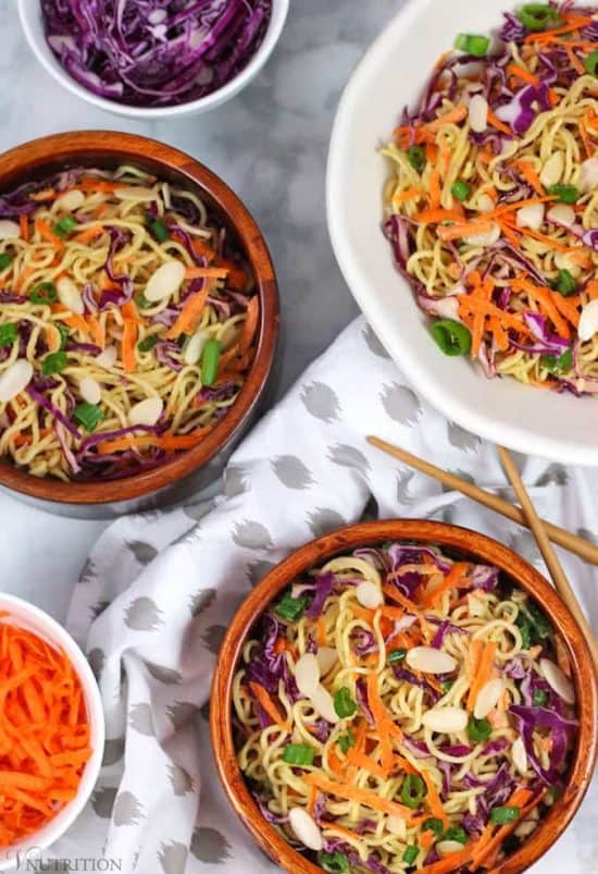 overhead shot of a a tablescape of Healthy Ramen Noodle Salad  in individual ceramic bowls and a large serving platter