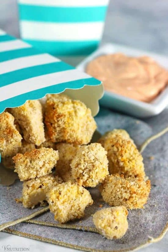 Air Fryer Popcorn Tofu nuggets spilling out of a blue and white striped cardboard snack container