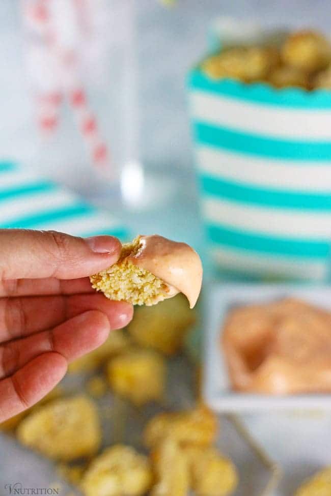 hand holding piece of Air Fryer Popcorn Tofu with a bit of sriracha mayo on it