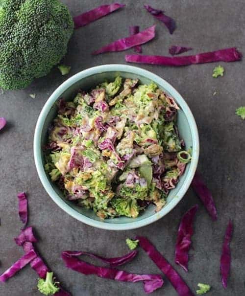 overhead shot of easy vegan broccoli slaw with broccoli and cabbage surrounding it for vegan sides for grilling