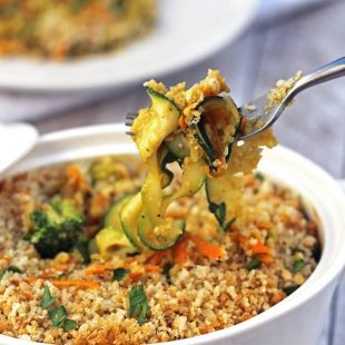 spoon of pumpkin vegetable bake removed from casserole dish.