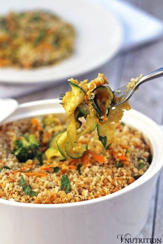 forkful of zucchini carrot vegetable casserole atop a full casserole dish