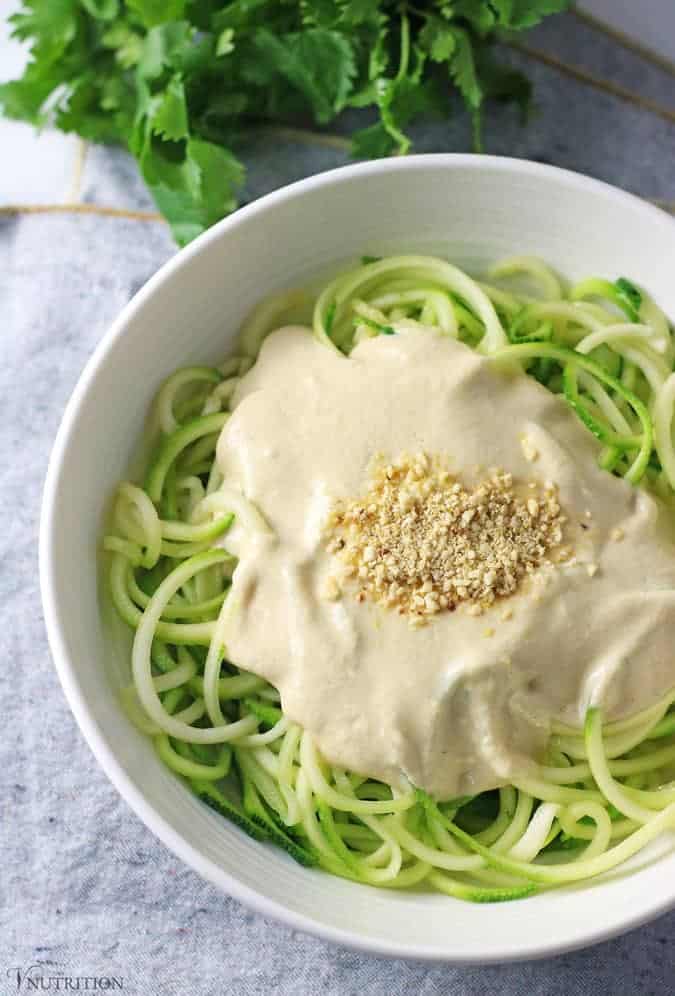 Overhead shot of Vegan Zucchini Pasta Alfredo with grey napkin and cilantro above