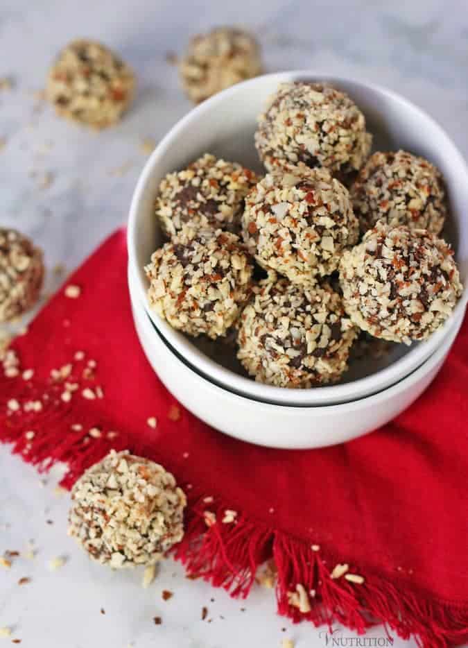 two bowls stacked filled with Chocolate Cherry Protein Balls on top of red napkin with more balls in background and foreground