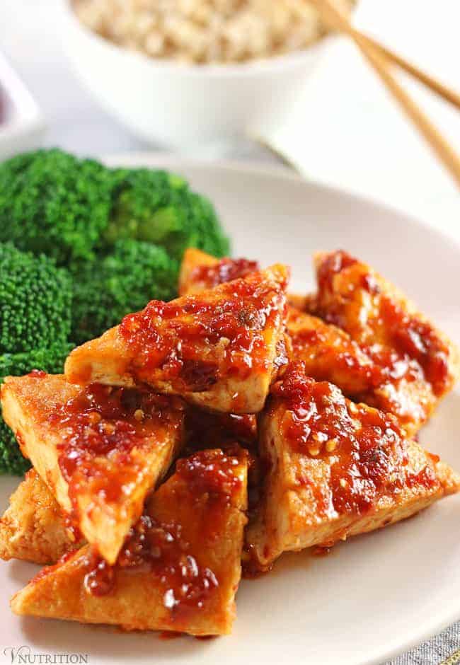 Tofu in Chili Garlic Sauce on a white plate with broccoli and brown rice