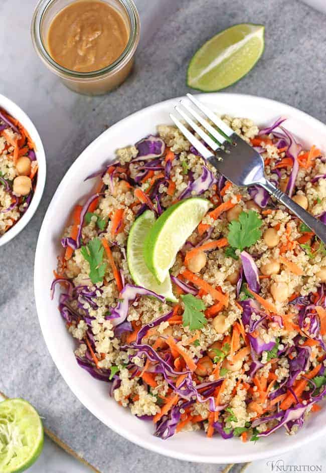 overhead shot of Thai Quinoa Salad in bowls with silver forks and a mason jar of extra creamy peanut dressing.