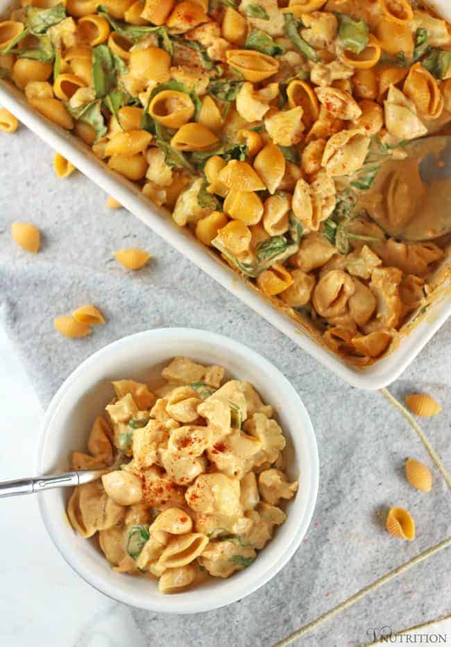 Buffalo Cauliflower Mac and Cheese in a white bowl on a grey napkin with a silver spoon.