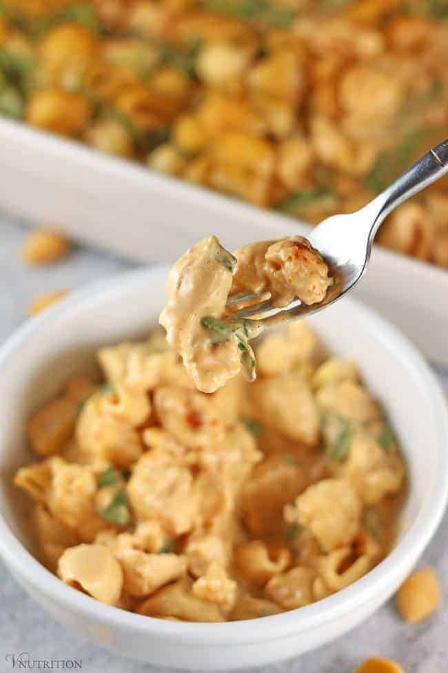 single forkful of vegan Buffalo Cauliflower Mac and Cheese with a bowl of it in the background. 