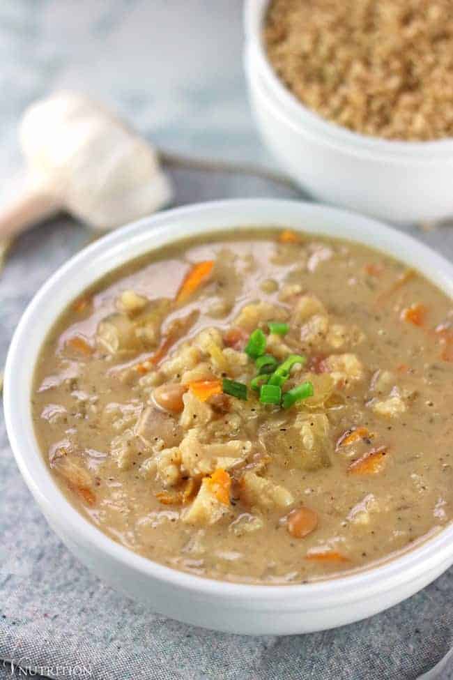 creamy bean and vegetable soup in a white bowl with a grey napkin