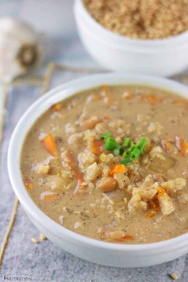 white bowl filled with vegan creamy vegetable soup and garnished with fresh chives