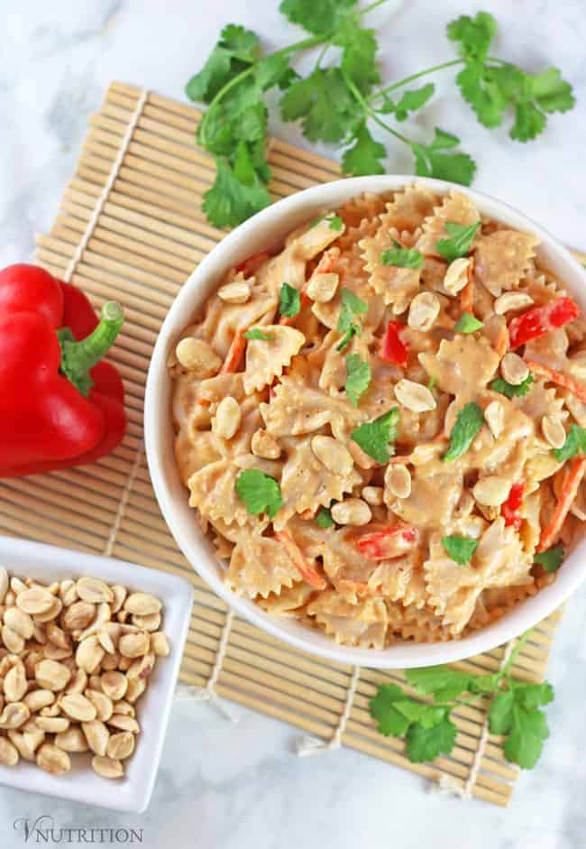 overhead shot of thai red curry mac and cheese with a whole red bell pepper and a bowl of peanuts on the side.