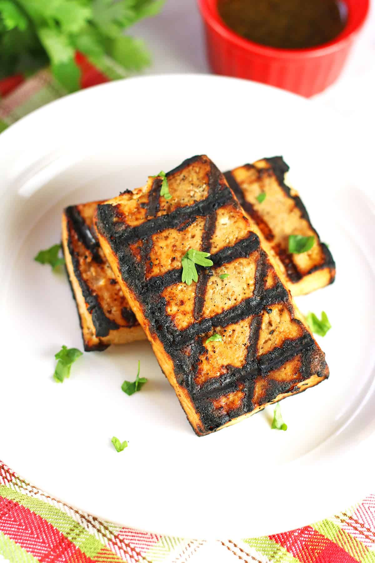 Two rectangles of grilled tofu steaks on a white plate garnished with parsley.