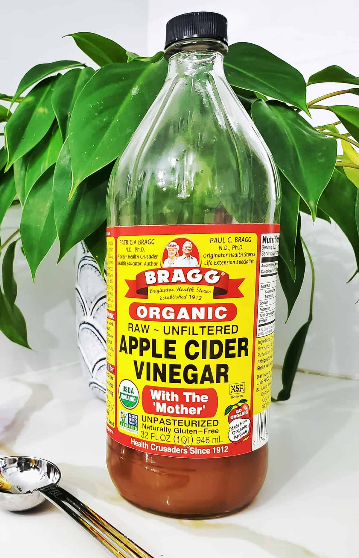 bottle of apple cider vinegar with a plan and measuring spooon