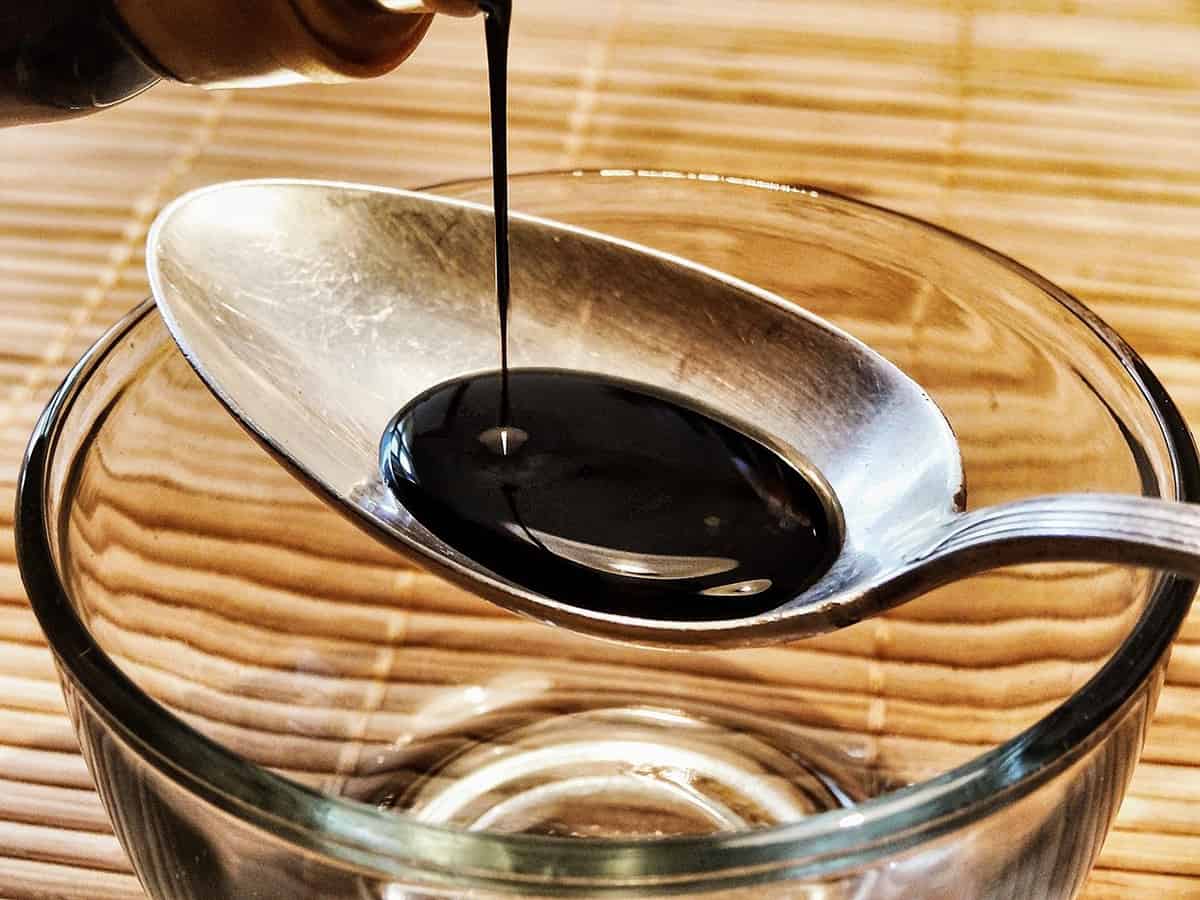 pouring tamari or soy sauce on a spoon over a dish