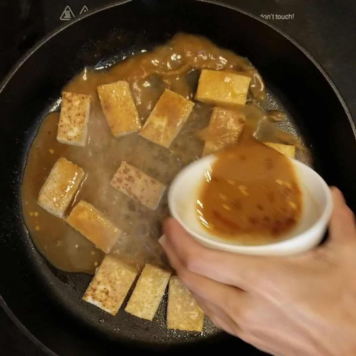 pouring sauce on fried tofu