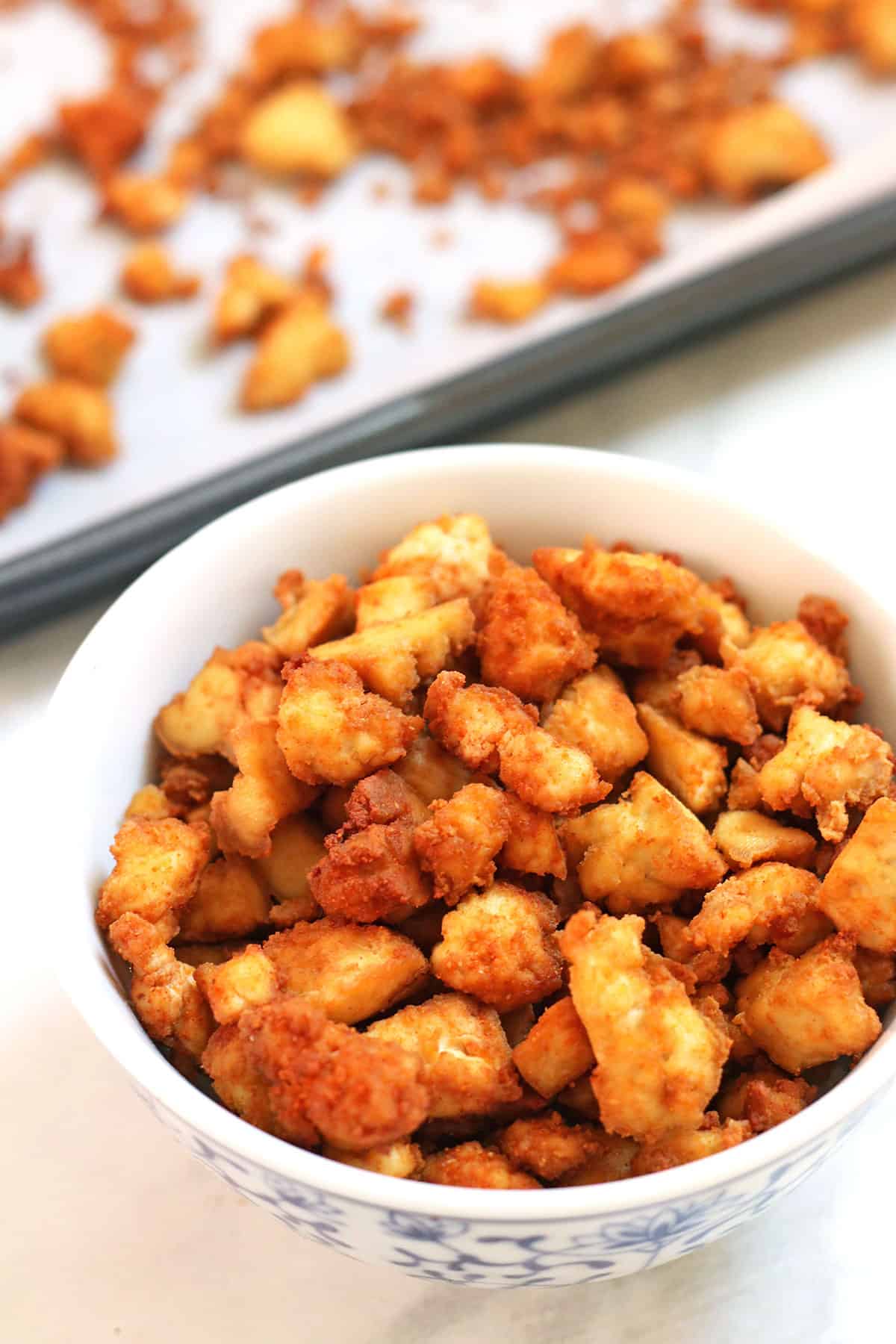 tofu crumbles in a bowl and on sheet pan