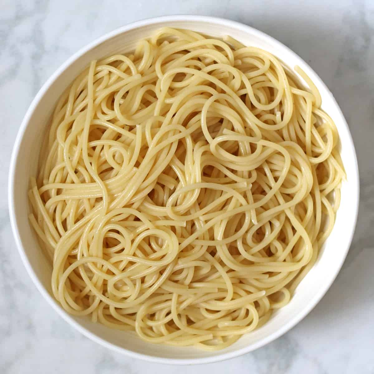 cooked spaghetti in a white bowl.