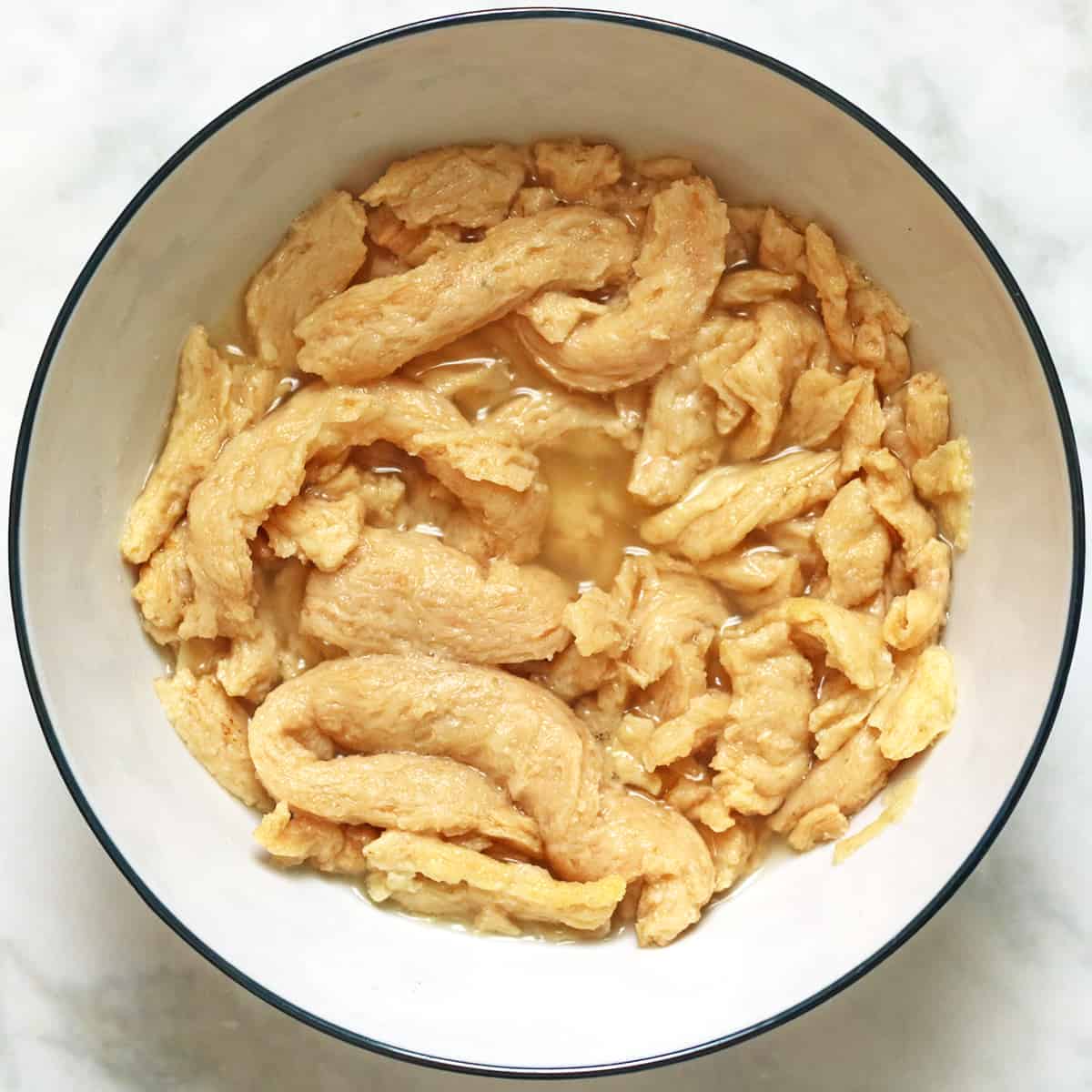 soy curls reconstituting in a bowl of water