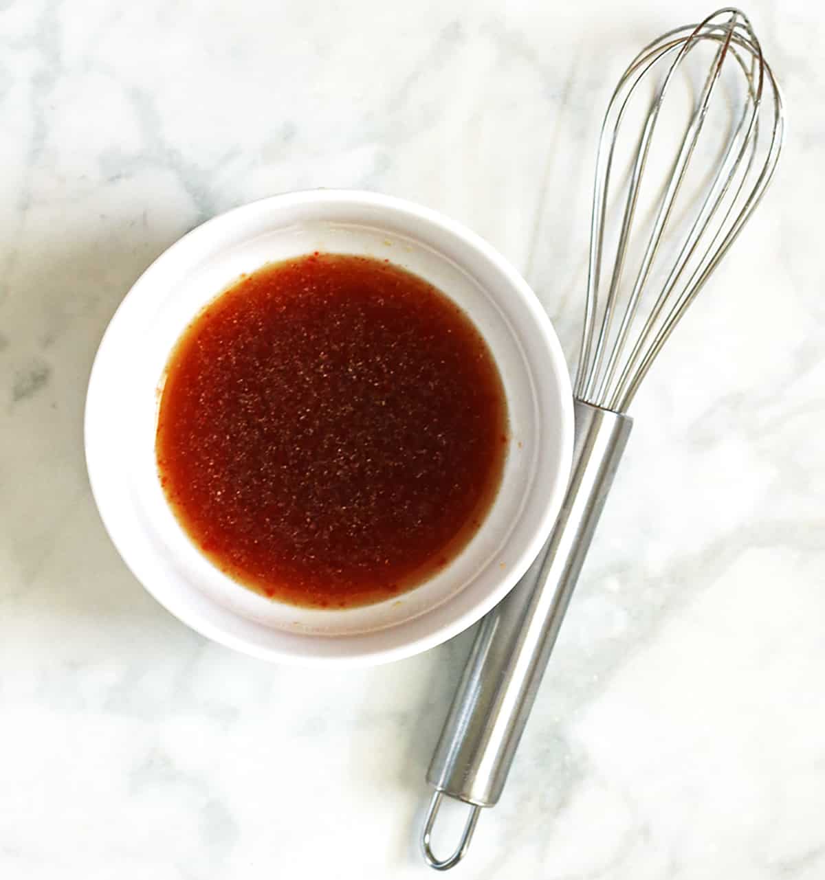 flavoring sauce for vegan meatless crumbles recipe in white bowl with whisk.