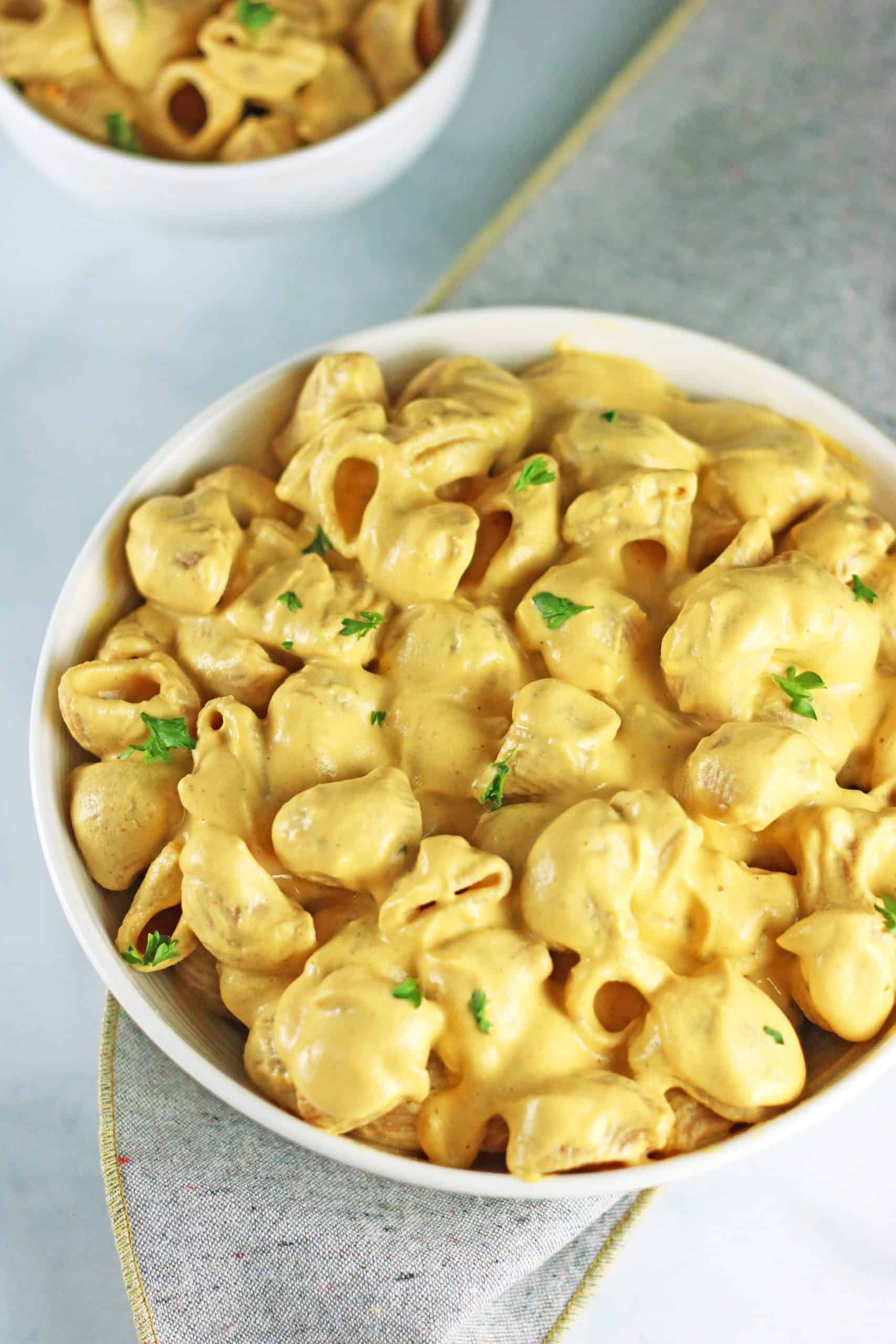 butternut squash mac and cheese in white bowl with smaller bowl of pasta.