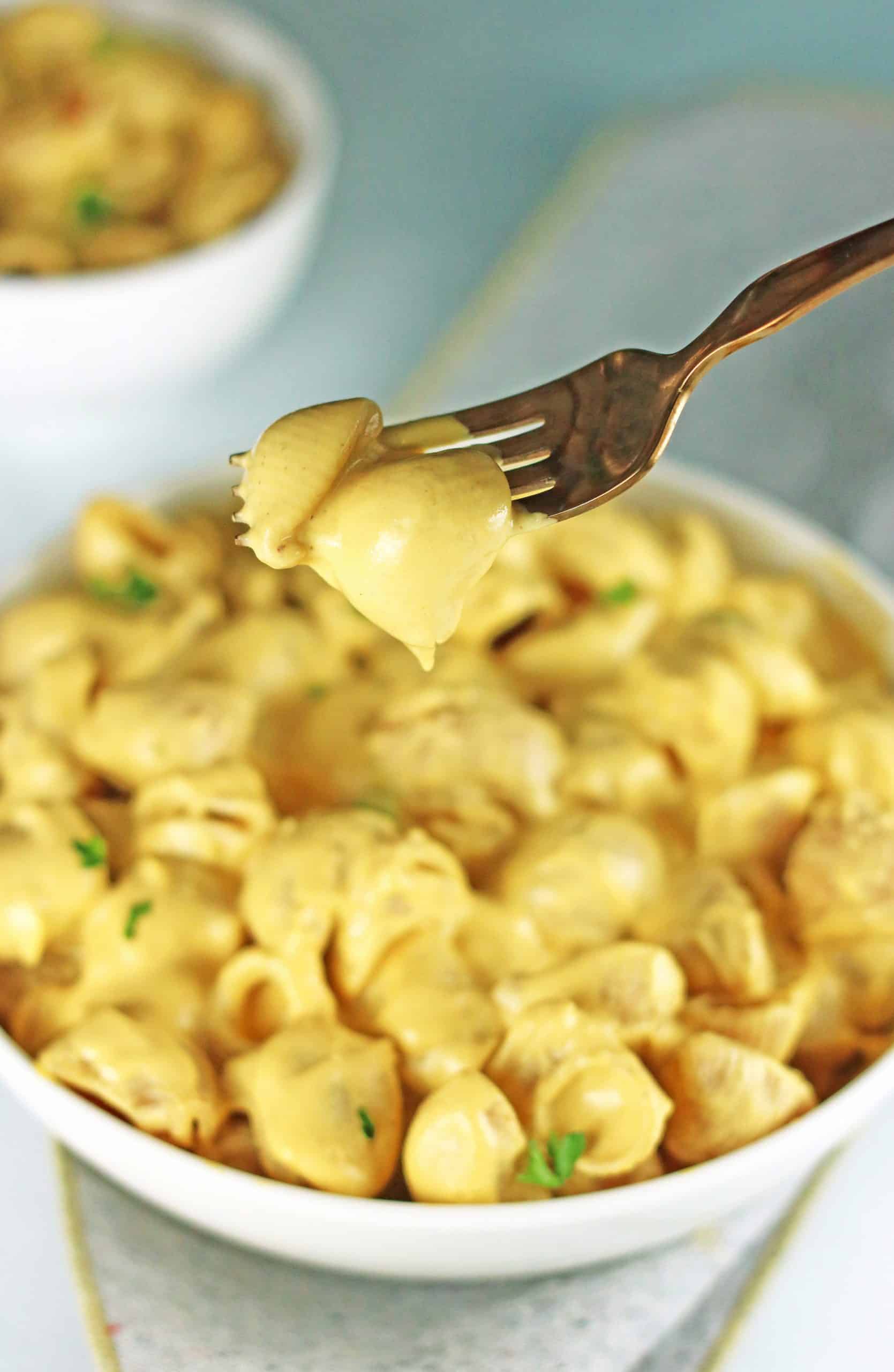 butternut squash pasta on fork with bowl of noodles in background.