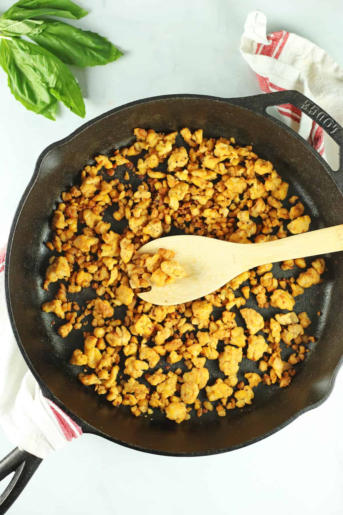 vegan meatless crumbles made with tempeh in black skillet wit wooden spoon.