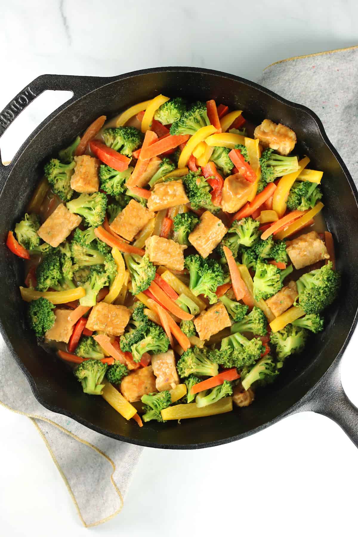 tempeh stir fry in pan with gray napkin underneath.