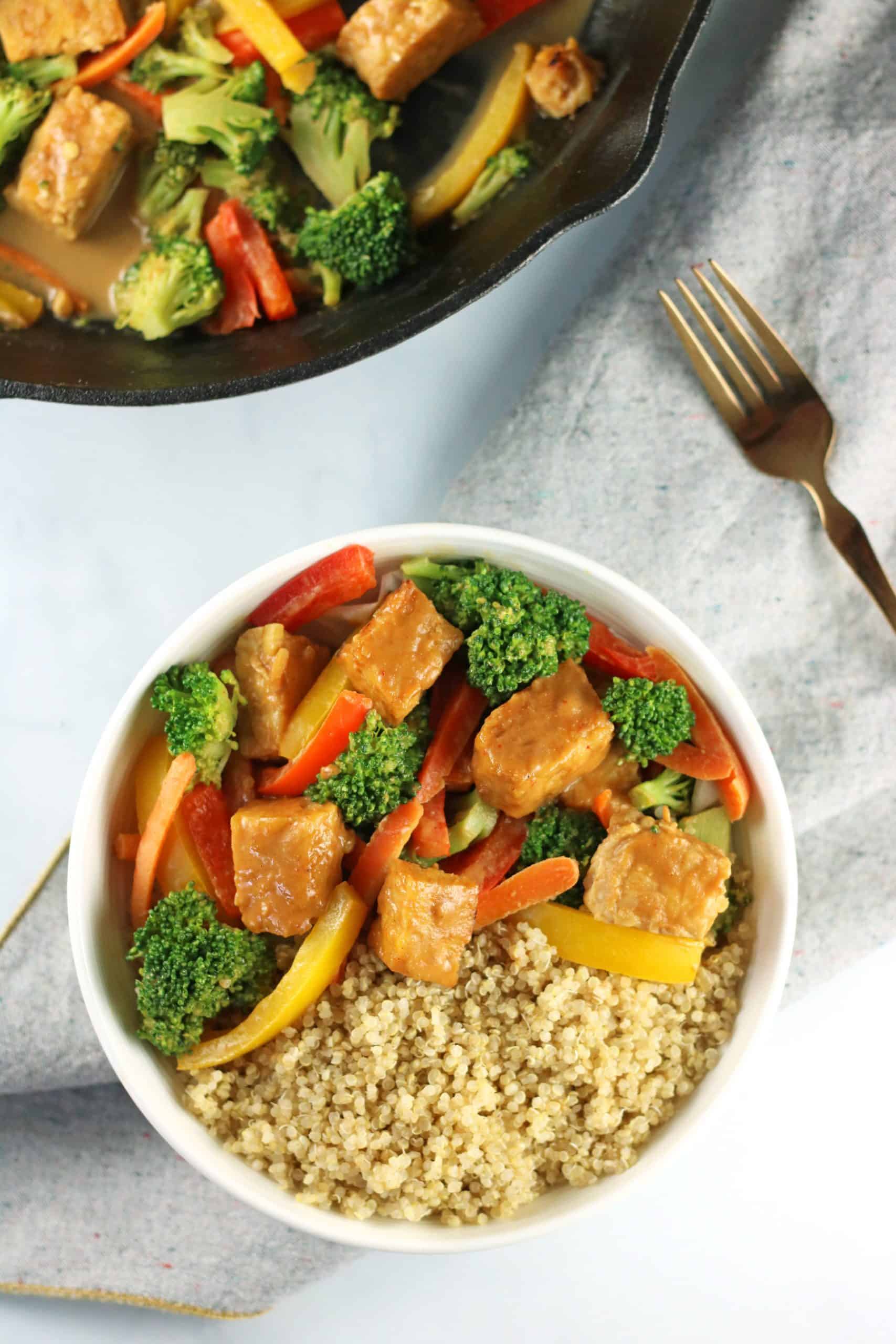 overhead of tempeh stir fry in bowl with quinoa and in a skillet with fork and napkin.