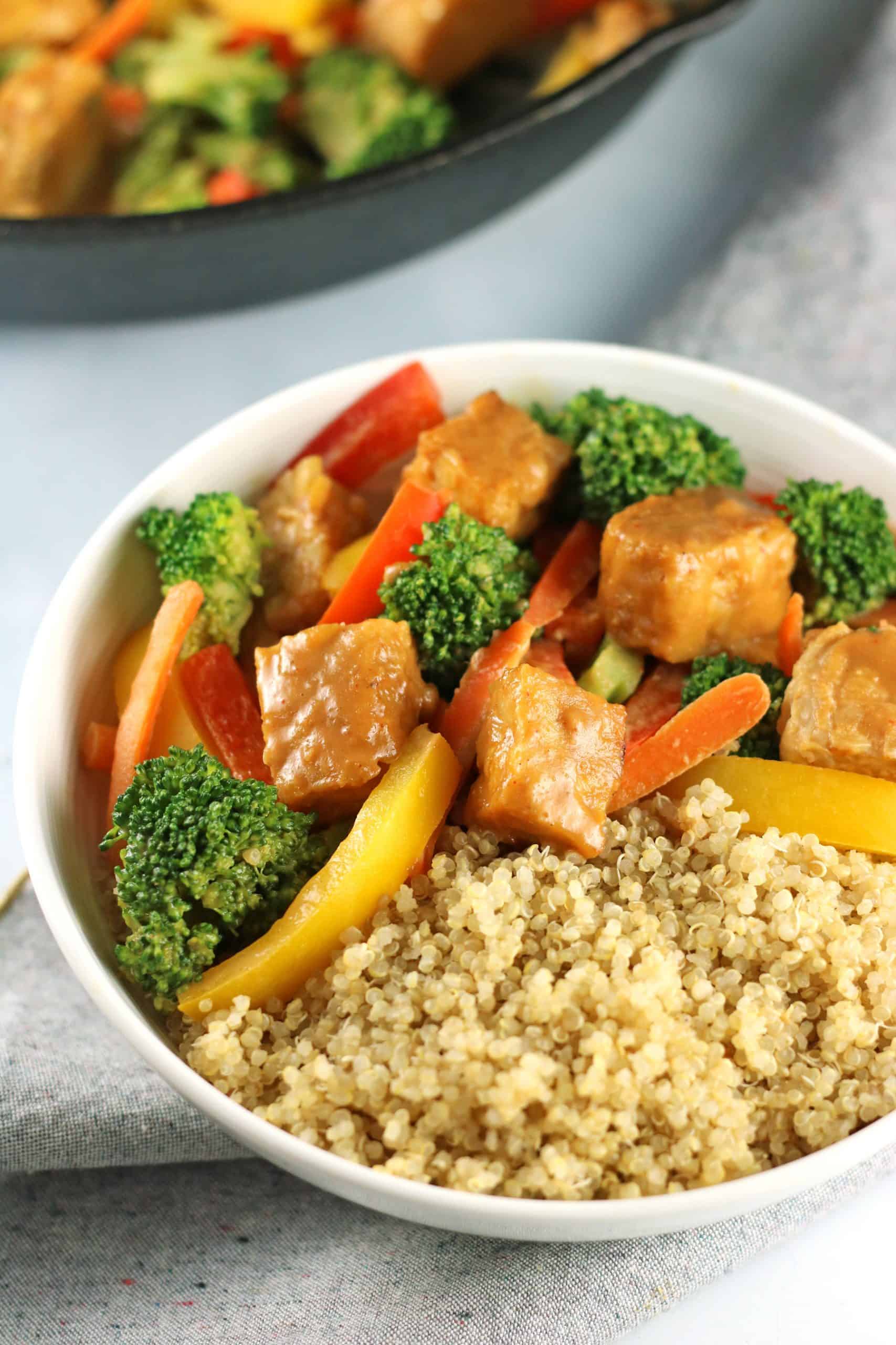 tempeh stir fry in white bowl with quinoa.