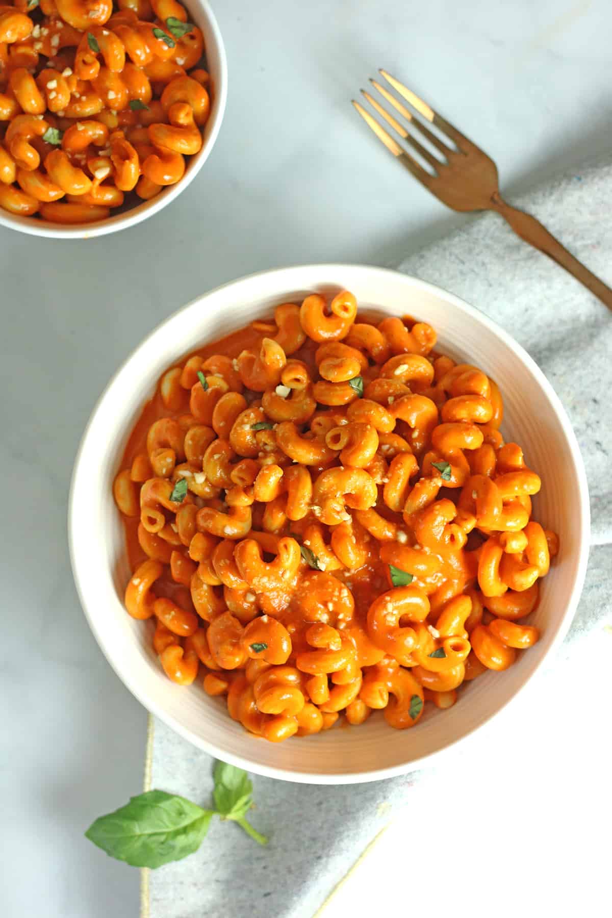 vegan roasted red pepper sauce in white bowls with gold fork.