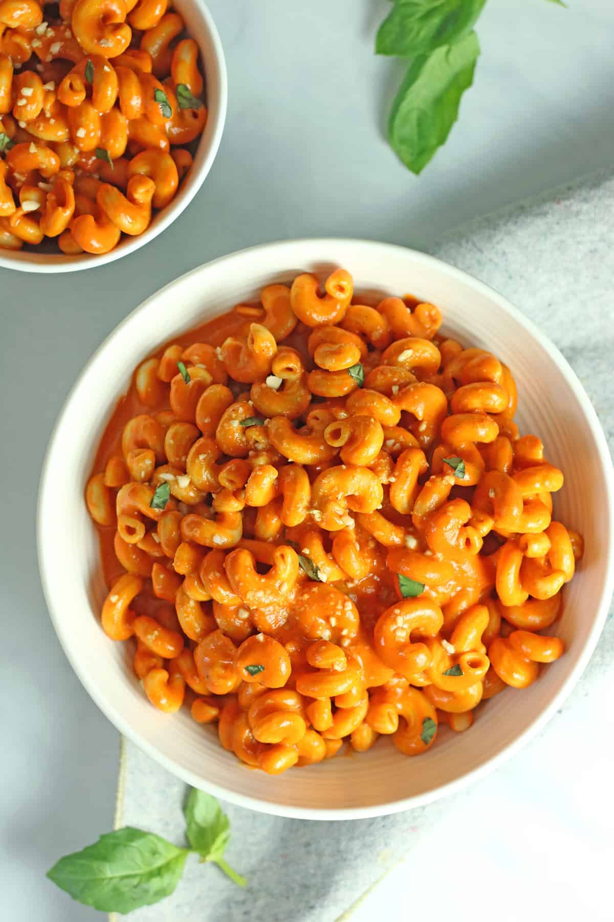 overhead shot of creamy vegan roasted red pepper pasta in white bowls.