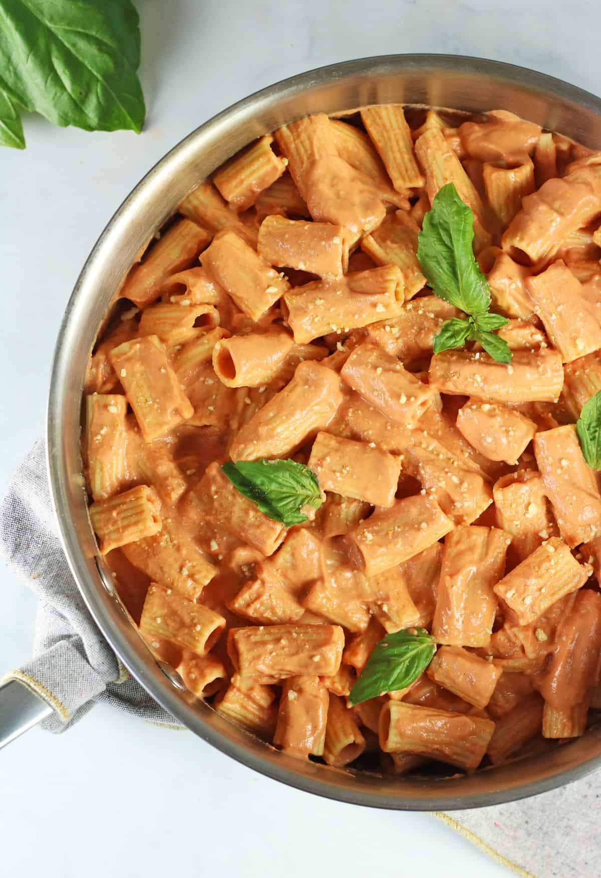 closeup of vegan vodka alla pasta in a pan with fresh basil.