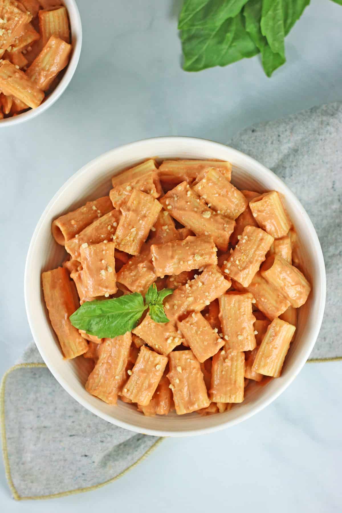 vegan vodka pasta in white bowls with gray napkin.