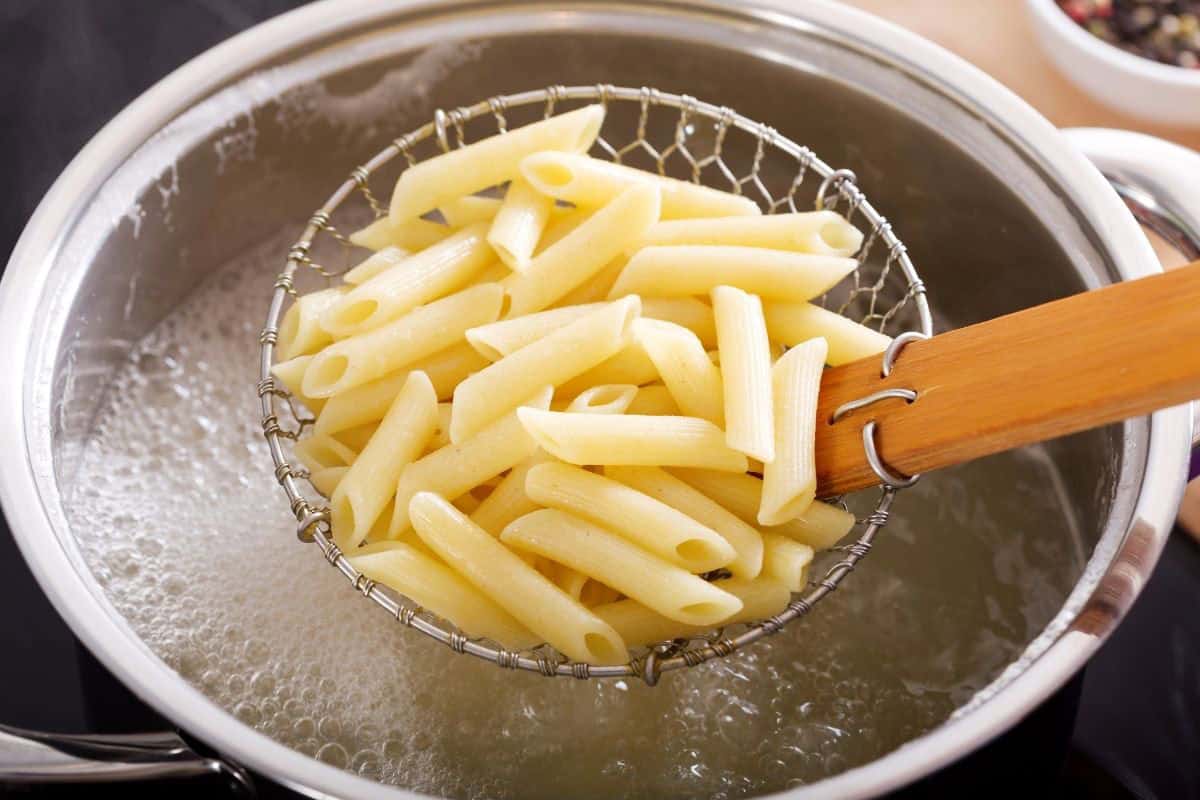 penne pasta draining over pot